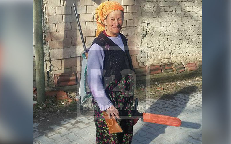 Omuzda tüfek, elde motorlu testere çalışmak onu yıldırmıyor